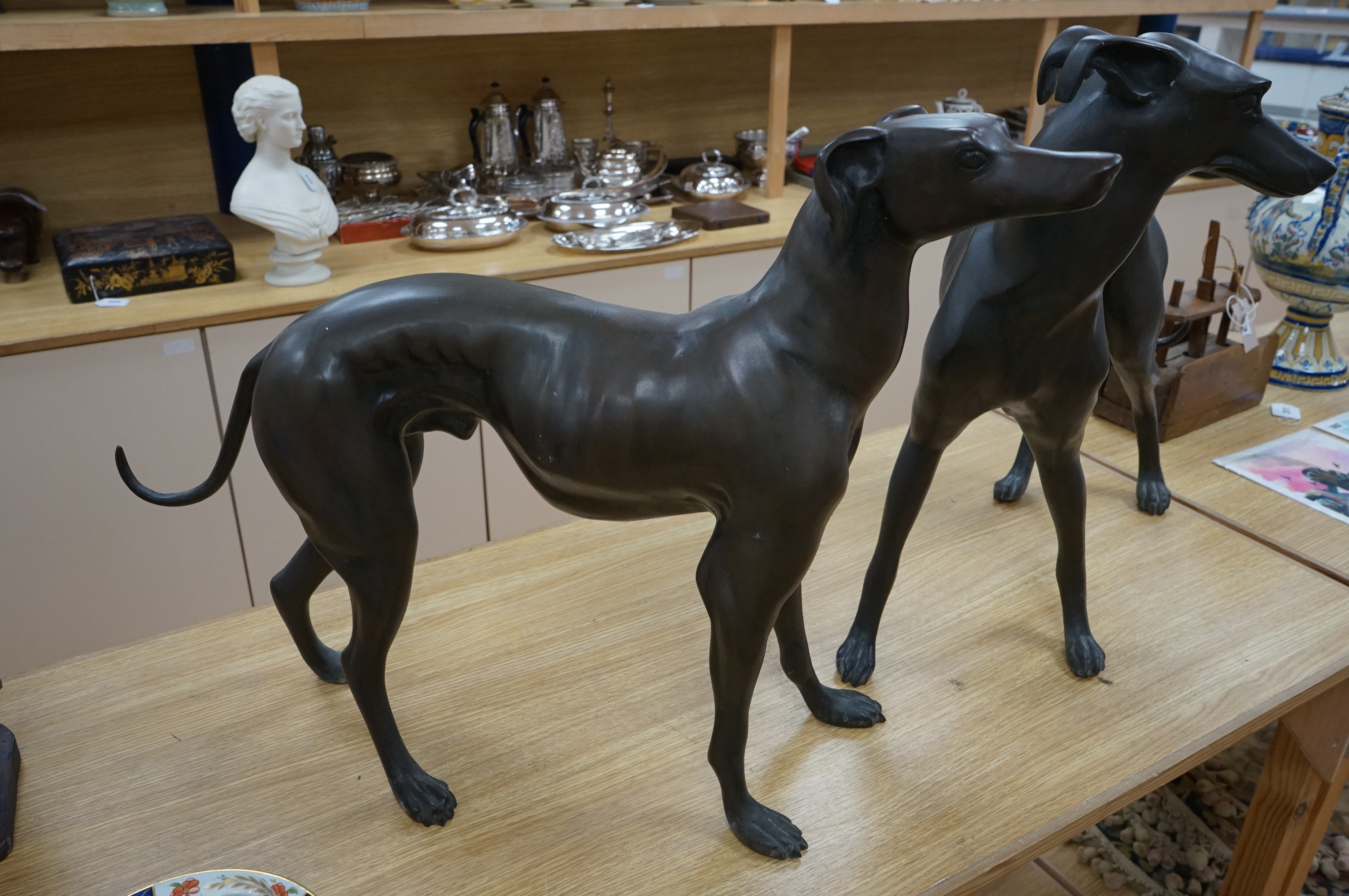 A pair of modern bronze greyhounds, approximately 66cm wide x 53cm high and 49cm wide x 57cm high. Condition - good